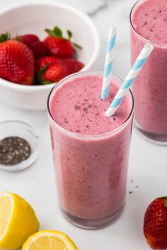 two glasses filled with smoothie next to strawberries and lemons