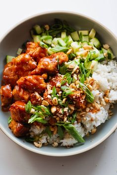 a bowl filled with rice, meat and veggies next to cucumbers