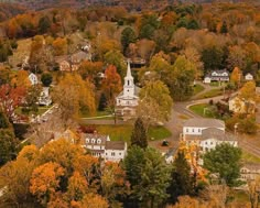 an aerial view of a small town surrounded by trees and mountains in the fall season