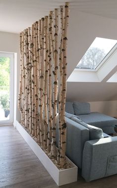 a living room filled with furniture and a tall tree trunk wall next to a window