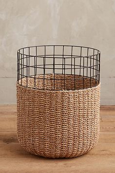 two wicker baskets sitting on top of a wooden table next to each other and one has a wire basket in the middle