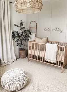 a baby's room with a wicker crib and round ottoman