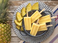 pineapple pops on a plate next to sliced pineapples