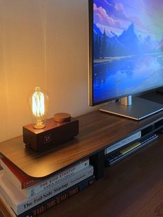 a television sitting on top of a wooden table next to a lamp and books in front of it