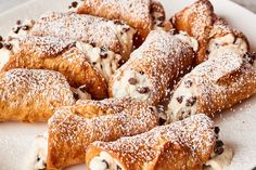 a white plate topped with croissants covered in powdered sugar and chocolate chips