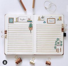 an open planner with pencils and other items on the table next to it,