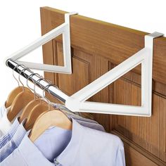 a rack with clothes hanging on it next to a closet door and wooden doors behind it