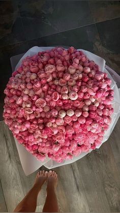 a person standing next to a large bouquet of flowers on top of a wooden floor