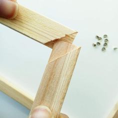 a person holding a piece of wood in their hand with beads on the other side