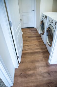 two washers and dryer in a room with wood flooring on the ground