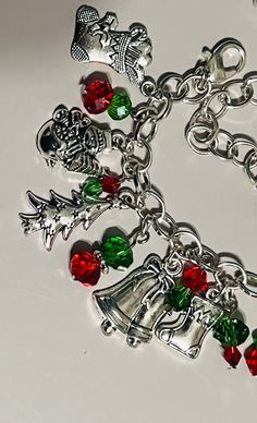 Handmade just for you This chunky handmade charm bracelet is a must have for this Holiday Season. It has 11 silver zinc metal alloy charms.  Accented with red and green roundelle and bicone crystal beads with red pearls.  The red and green crystals add a touch of vibrant color and sparkle to the bracelet. The red crystals represent the joy and warmth of the holiday season, while the green crystals symbolize the evergreen trees and the hope of new beginnings. These crystals are carefully placed on the charms, creating a dazzling effect when they catch the light. Each charm on the bracelet is uniquely crafted to representing a variety of  different Christmas symbols. These charms hang gracefully from the bracelet, creating a delightful jingling sound with every movement. This bracelet is a l Christmas Symbols, Handmade Charm Bracelets, Holiday Bracelets, Bracelet Christmas, Christmas Bracelet, Evergreen Trees, Christmas Charms, Red Crystals, Christmas Jewelry