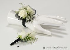 two white roses and greenery are placed on the arm of a bride's hand