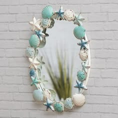 there is a mirror with shells on it and a plant in the corner next to it