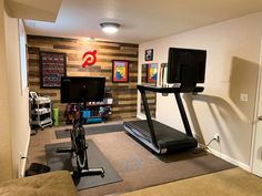 a home gym with treadmills, exercise equipment and television on the wall behind it