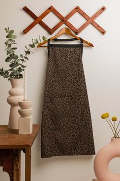 a leopard print dress hanging on a wall next to vases with flowers in them