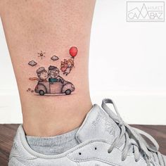 a small tattoo on the ankle of a girl with an air balloon flying over her head