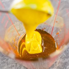 a blender filled with liquid being poured into the bowl for making an orange smoothie