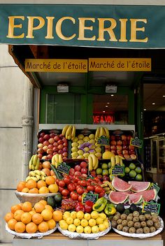 a fruit stand with many different types of fruits on display in front of the store