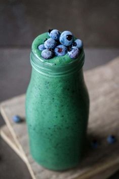 a green smoothie topped with blueberries in a mason jar