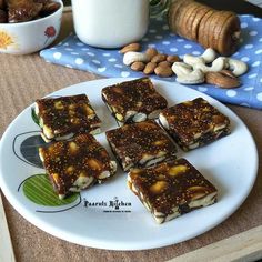 several pieces of dessert on a plate with nuts and milk in the backgroud