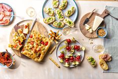 an assortment of appetizers and snacks on plates with utensils laid out