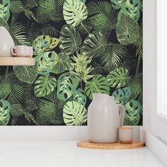 the wallpaper in this kitchen is painted with tropical leaves