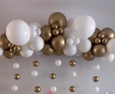 gold and white balloons are hanging from the ceiling