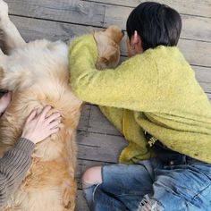 a person sitting on the ground petting a large dog's head with his paws