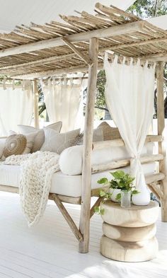 an outdoor bed with white curtains and pillows