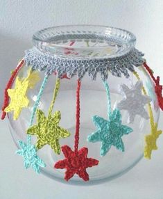 a glass bowl with crocheted stars hanging from it