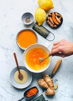 the ingredients to make this soup are laid out on a marble counter top, including carrots and ginger