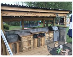 an outdoor bbq with grill, table and chairs