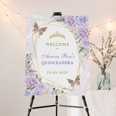 a welcome sign with purple flowers and butterflies in front of a white backdrop that reads welcome to the queen's quincaanera