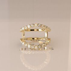 a gold ring with white stones on the inside and in the outside, sitting on a reflective surface