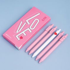 four pink and white pens sitting next to each other on top of a blue surface