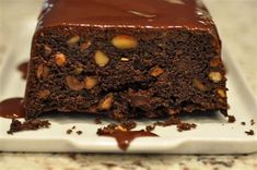 a piece of chocolate cake on a white plate with caramel drizzle and nuts