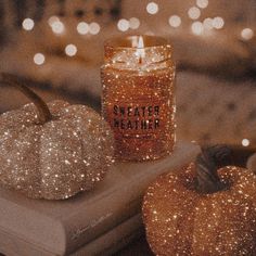 two glitter pumpkins and a candle on a table