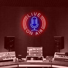 a recording studio with microphones and sound equipment in front of a live on air neon sign