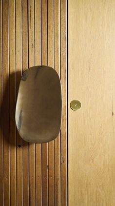 a wooden door with a metal object on it's side next to a wood paneled wall