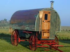 an old fashioned covered wagon is parked in the grass