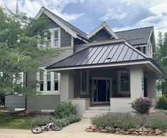 a bicycle is parked in front of a house with a metal roof and shingled windows