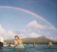 a group of people in the water with surfboards under a rainbow