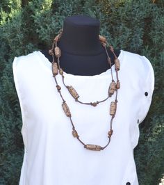 a woman wearing a white shirt and brown beaded necklace on top of a mannequin