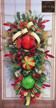 a christmas wreath hanging on the side of a door decorated with red, green and gold ornaments