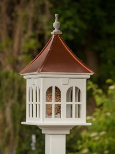 a white bird feeder on top of a pole