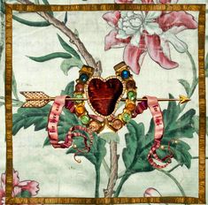 an embroidered wall hanging with a heart and arrow on it, surrounded by pink flowers