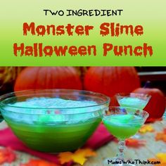 two glasses filled with green slime sitting on top of a table next to pumpkins