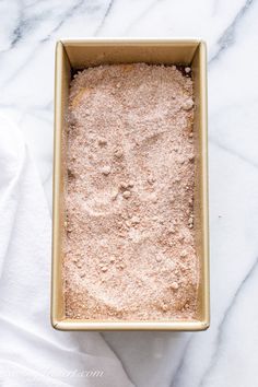 a pan filled with food sitting on top of a white marble counter next to a towel