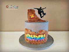 a birthday cake with a skateboarder on the top and rainbow letters in the bottom