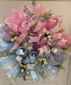 a pink and blue wreath with bows hanging on a door